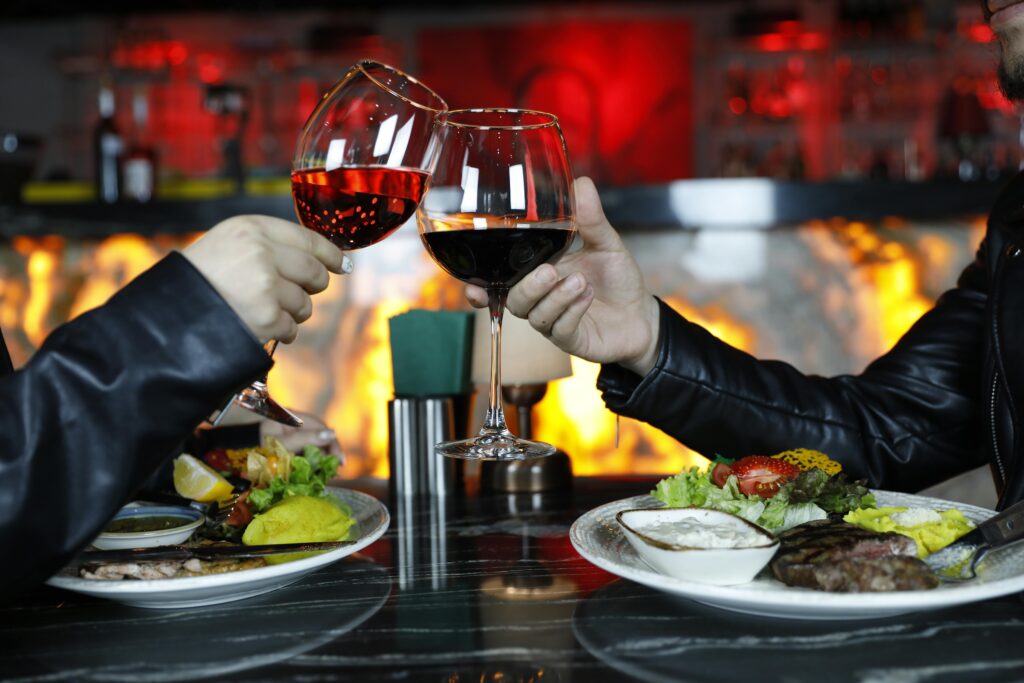 A dinner table with a couple clinking their wine glasses.
